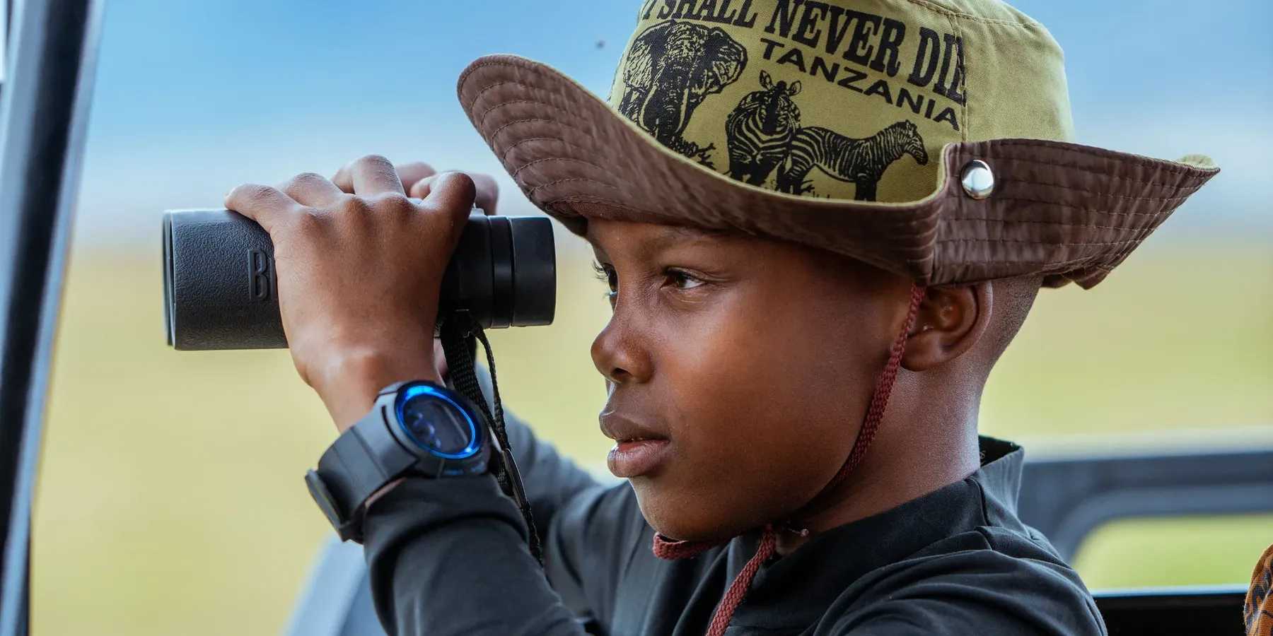 A young traveler spotting wildlife from a TanzaLux safari vehicle